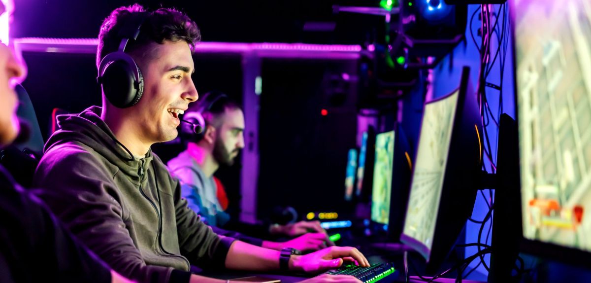 Männer mit Headsets spielen an PCs.