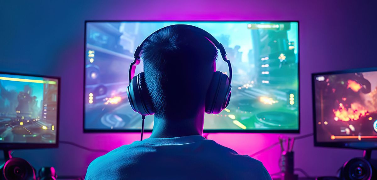 Mann sitzt mit Kopfhörern vor einem Gaming-Monitor