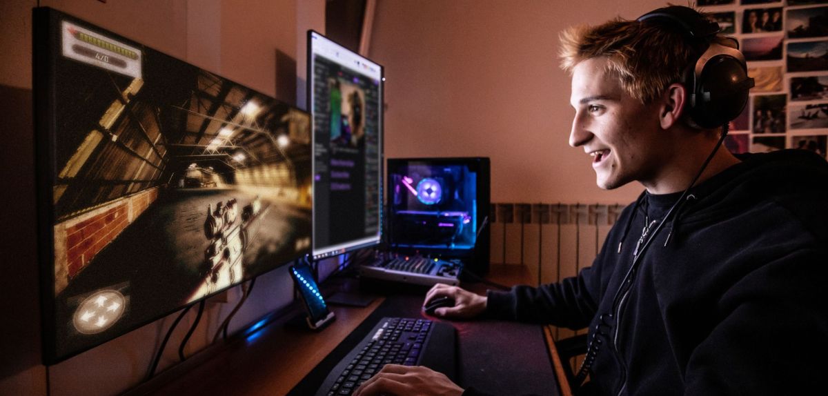 Mann sitzt vor einem Monitor und spielt einen Shooter