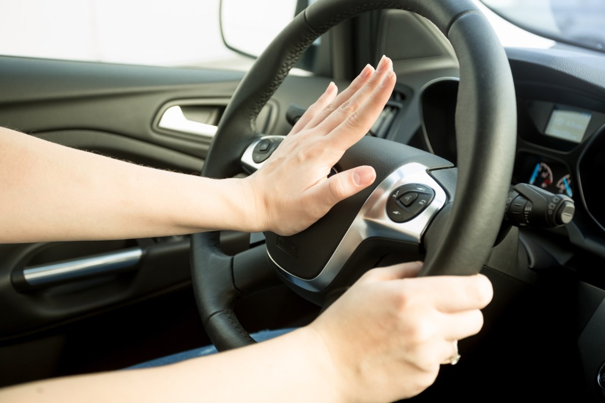 Frau drückt im Auto auf die Hupe