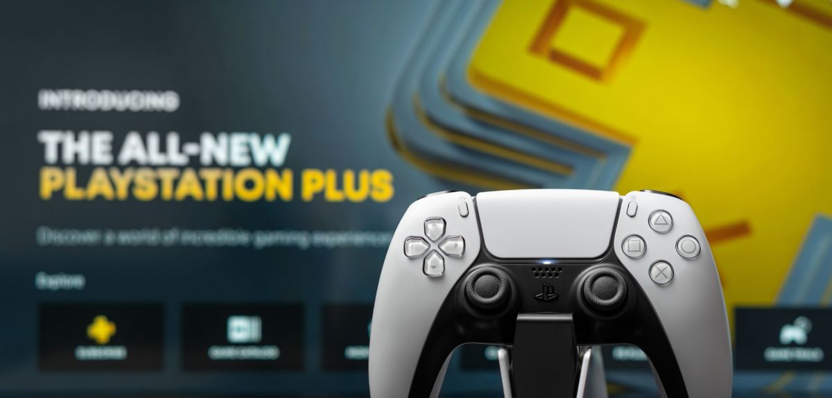 PS5-Controller, im Hintergrund Werbetafel für PS Plus.