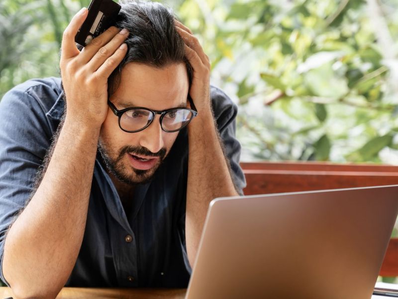 Mann schaut schockiert auf Laptop