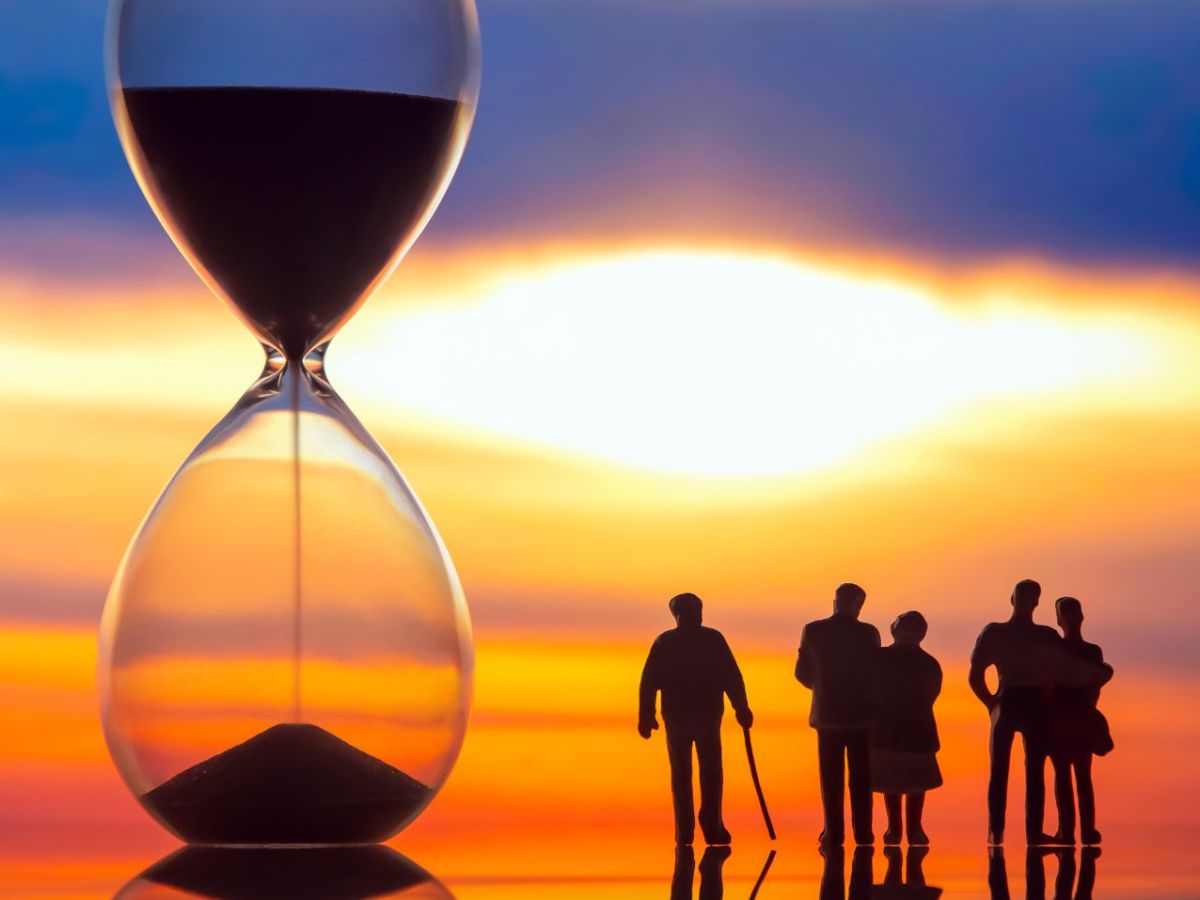 Eine große Sanduhr, daneben Silhouetten von Menschen.