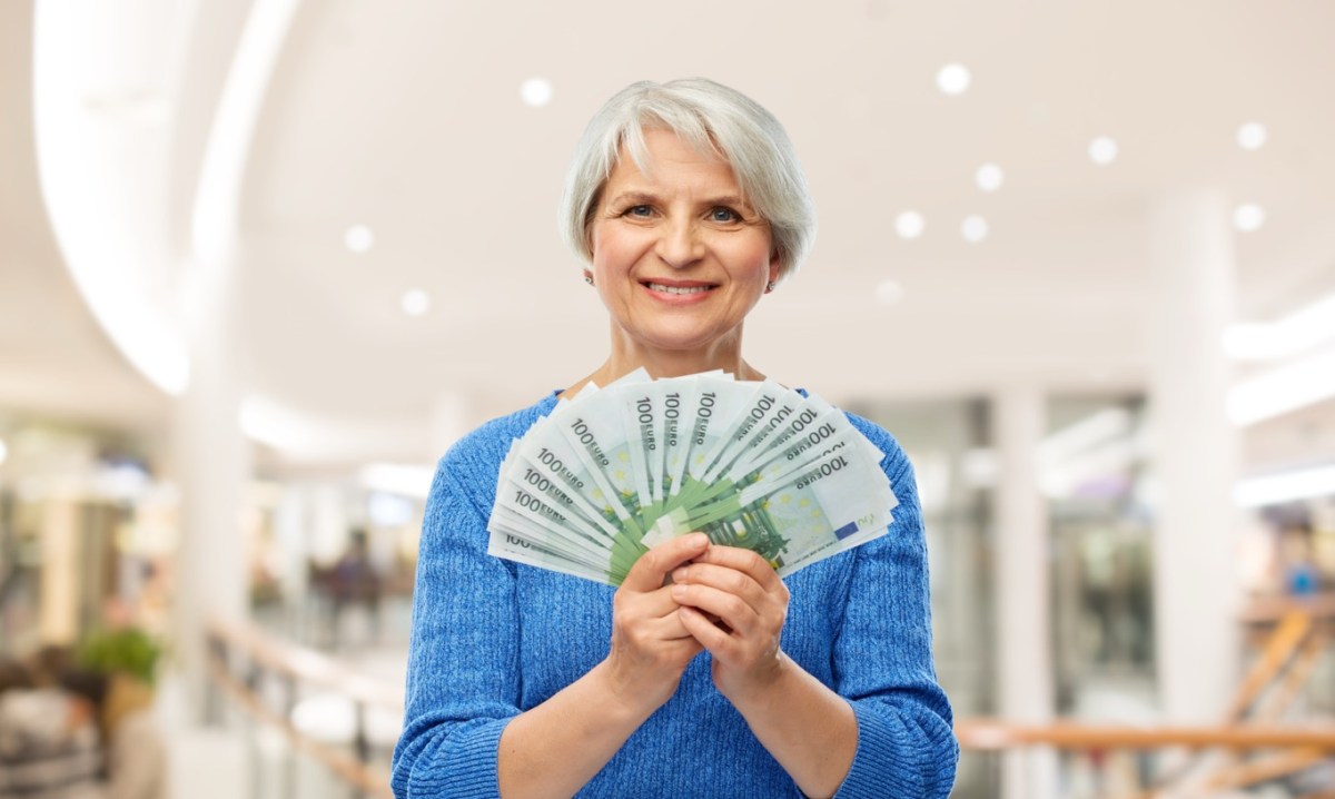 Ältere Frau hält Geldscheine hoch