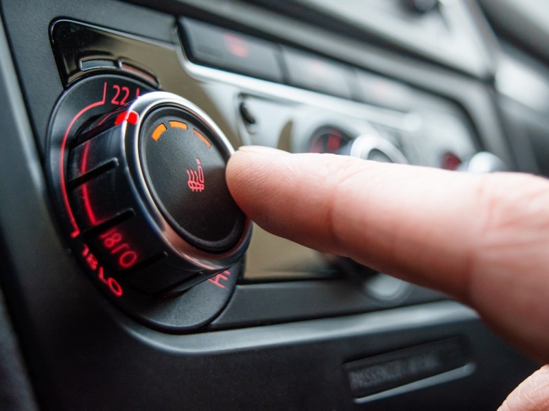 Person drückt den Knopf für die Autoheizung