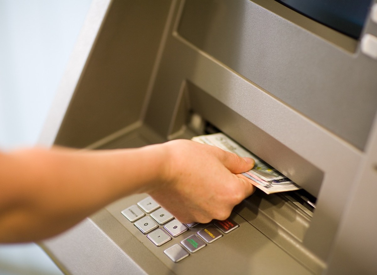 Person hebt Geld am Automaten ab