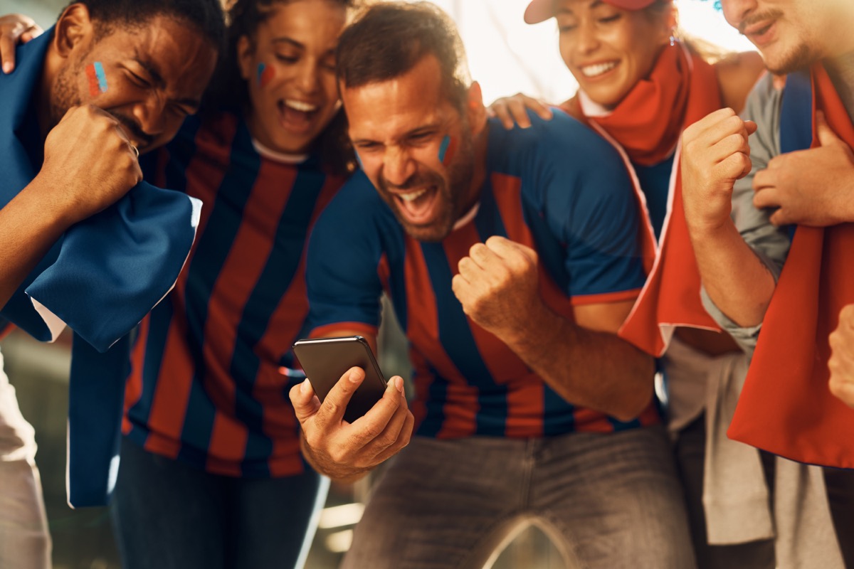 Fußball-Fans stehen begeistert vor einem Handy