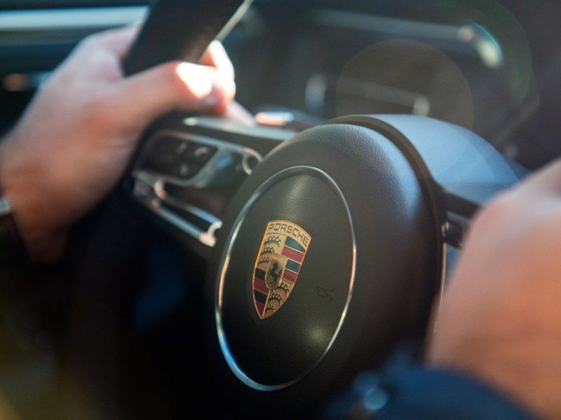 Mann hält das Lenkrad eines Porsche fest
