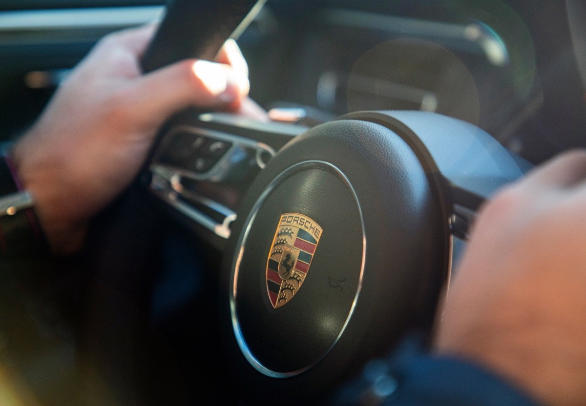 Mann hält das Lenkrad eines Porsche fest