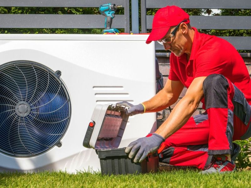 Fachkraft installiert Wärmepumpe im Garten