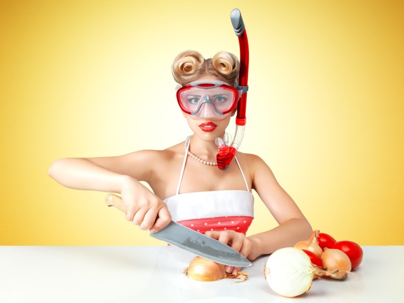 Frau schneidet Zwiebeln mit Taucherbrille