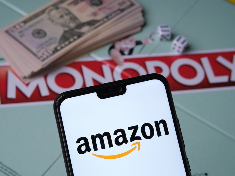 Amazon Logo erscheint auf Smartphone vor einem Monopoly-Spiel