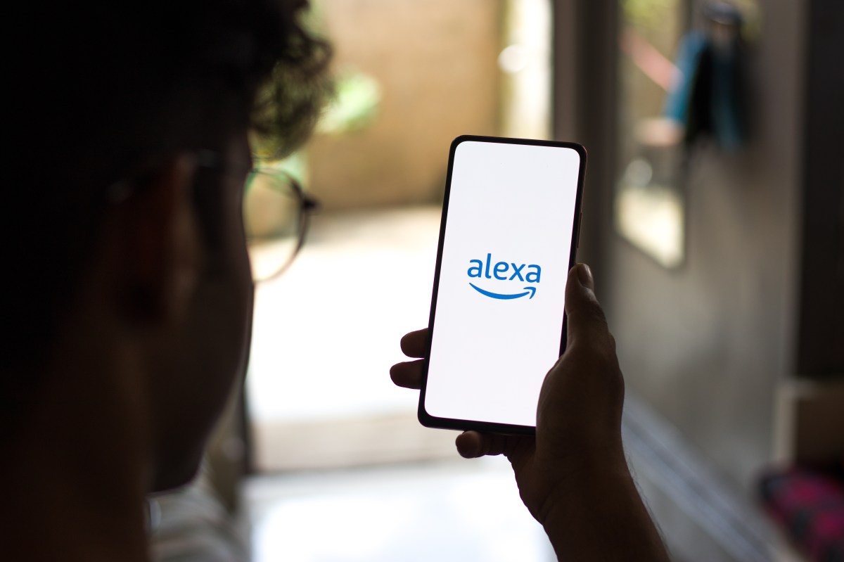Person hält ein Smartphone mit Alexa-Logo