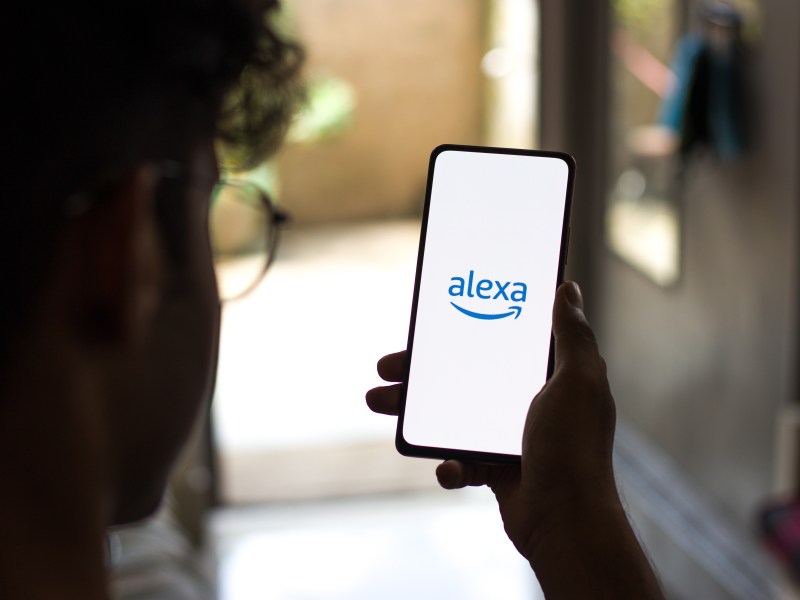 Person hält ein Smartphone mit Alexa-Logo