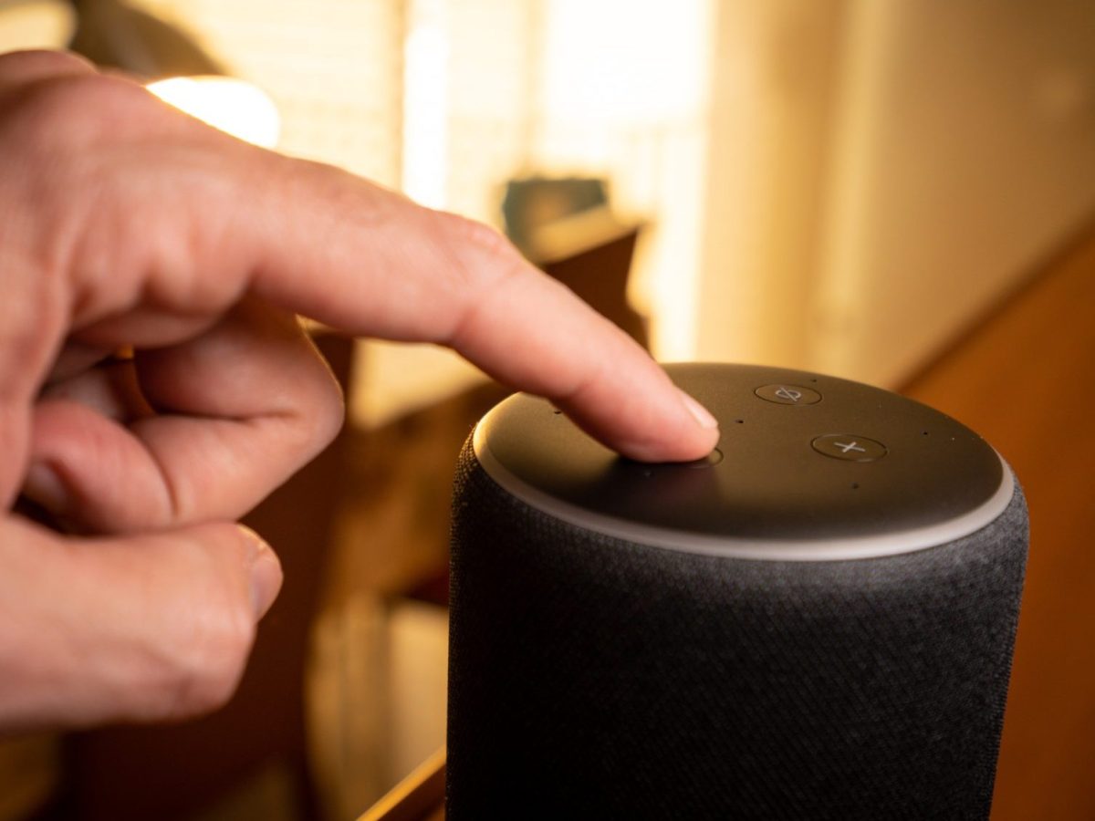 Hand tippt auf Amazon Echo.