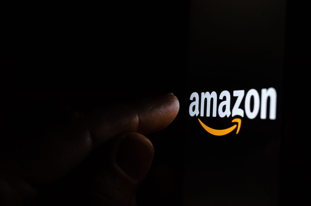 Person berührt Amazon Logo im Dunklen.