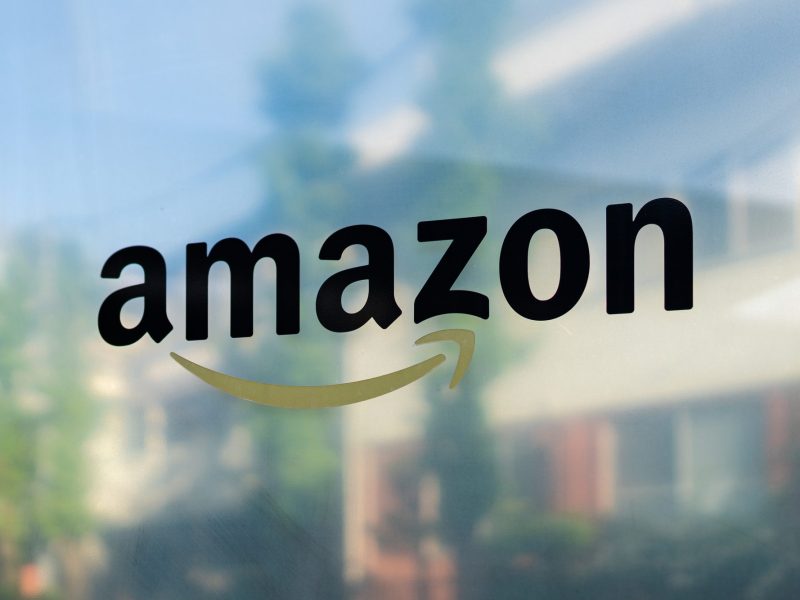 Das Amazon Logo erscheint auf spiegelnder Fläche.