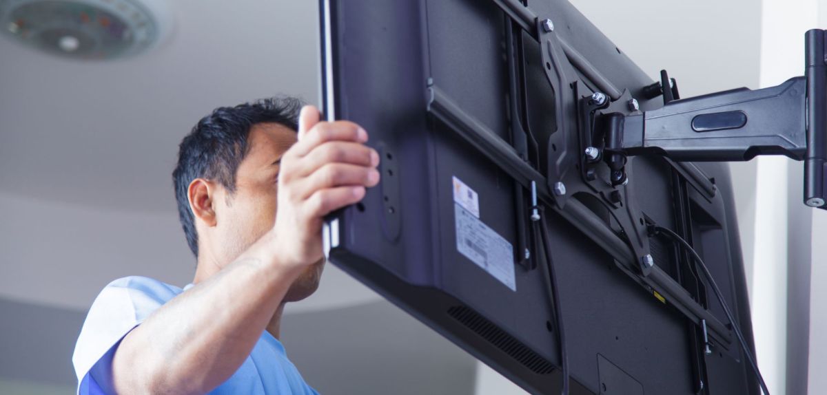 Mann wÃ¤hrend der Fernseher-Wandmontage.