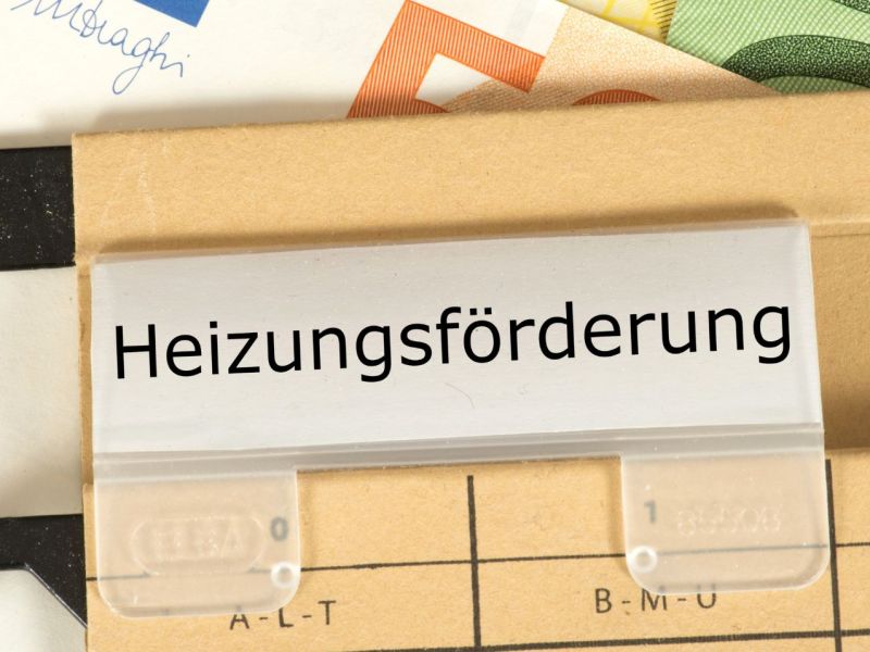 Kartei Heizungsförderung und im Hintergrund Geldscheine