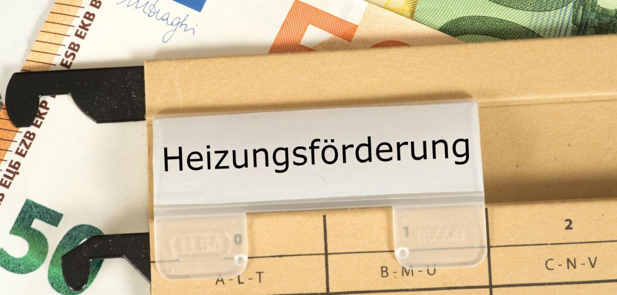 Kartei Heizungsförderung und im Hintergrund Geldscheine