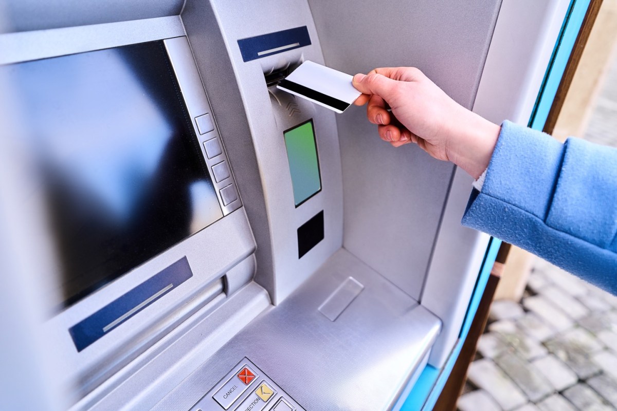 Mann hält EC-Karte vor einen Geldautomaten
