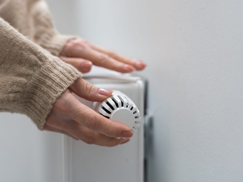 Frau dreht an einer Heizung, die nicht warm wird.