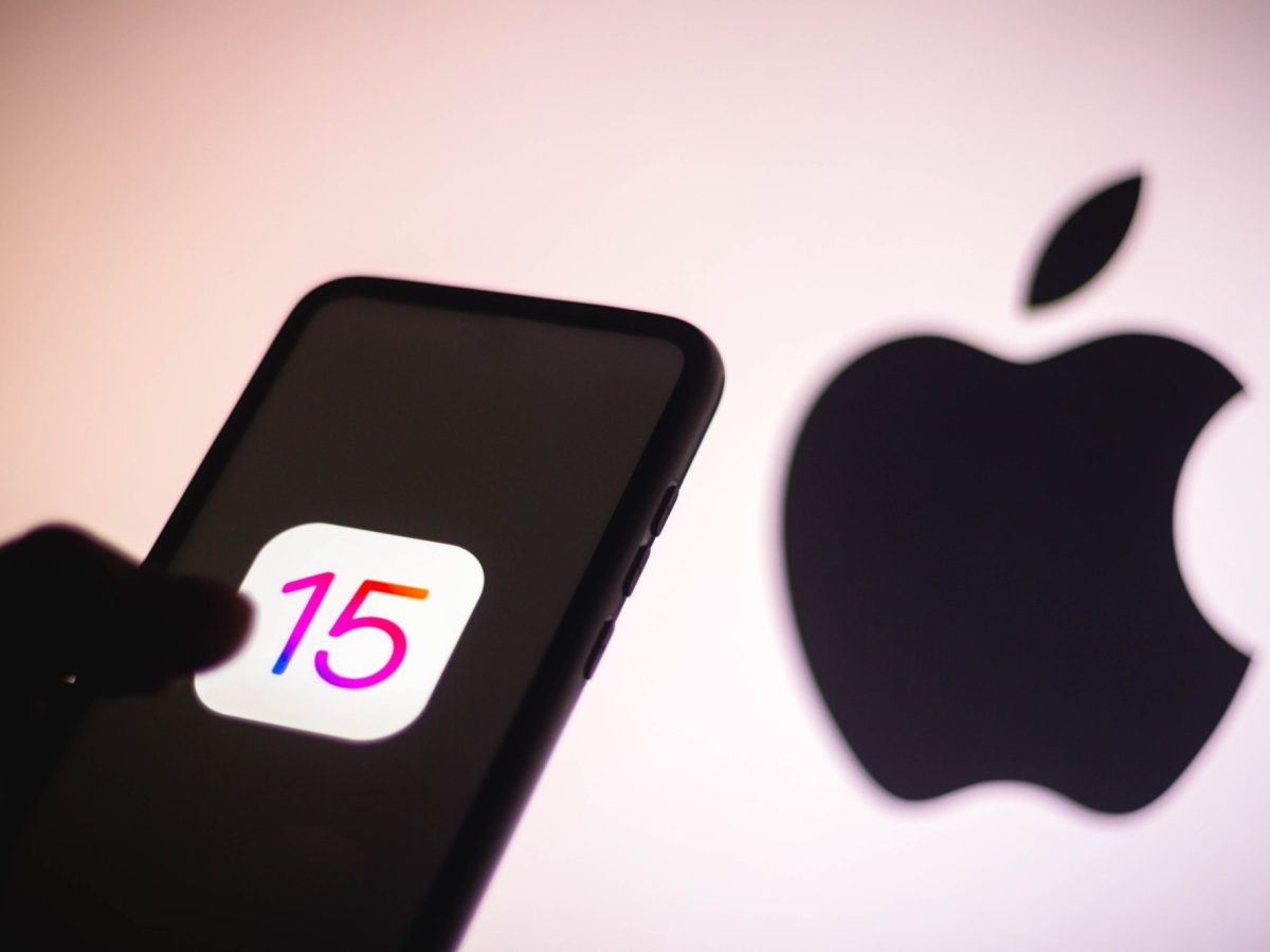 Das iPhone 15 als Schatten vor einem großen Apple Logo.