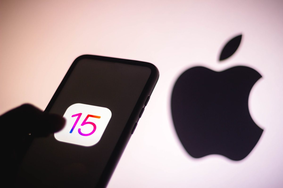 Das iPhone 15 als Schatten vor einem großen Apple Logo.