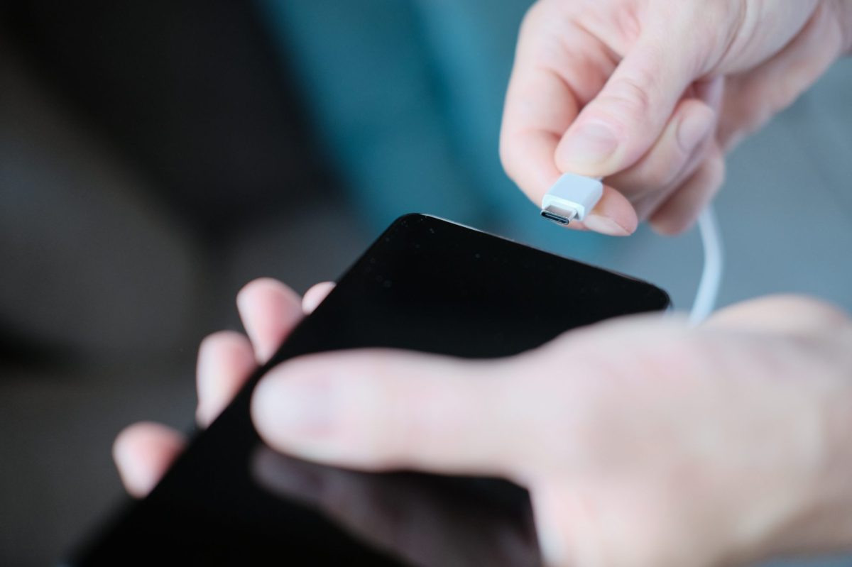 Person schließt Ladekabel an ein Smartphone an.