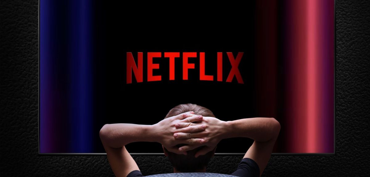 Person sitzt vor einem Fernseher mit dem Netflix-Logo auf dem Bildschirm.