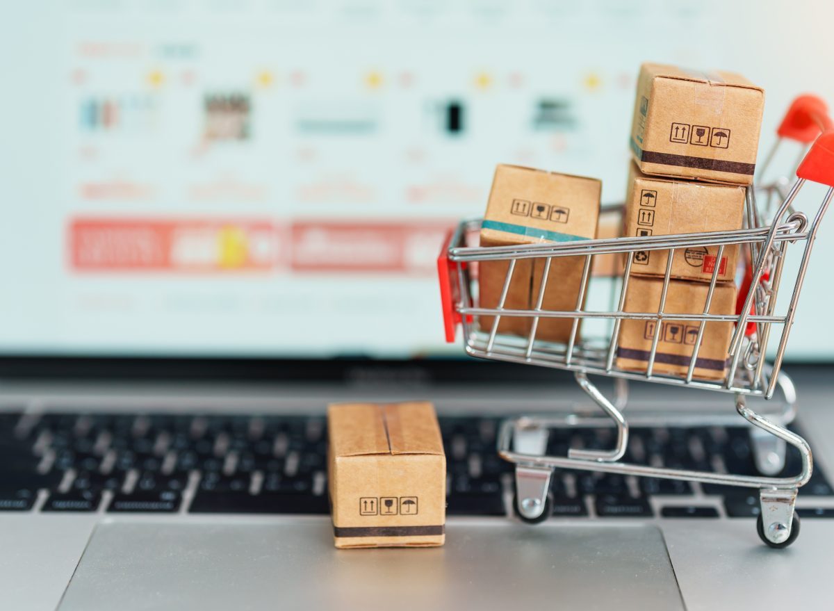 Symbolbild für Online-Shopping: Mit Paketen gefüllter Mini-Einkaufswagen steht auf Laptoptastatur.