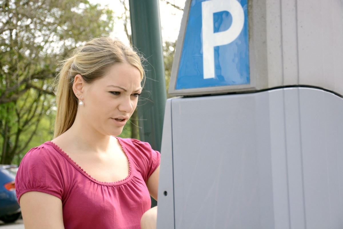 Junge Frau hat Probleme am Parkscheinautomaten