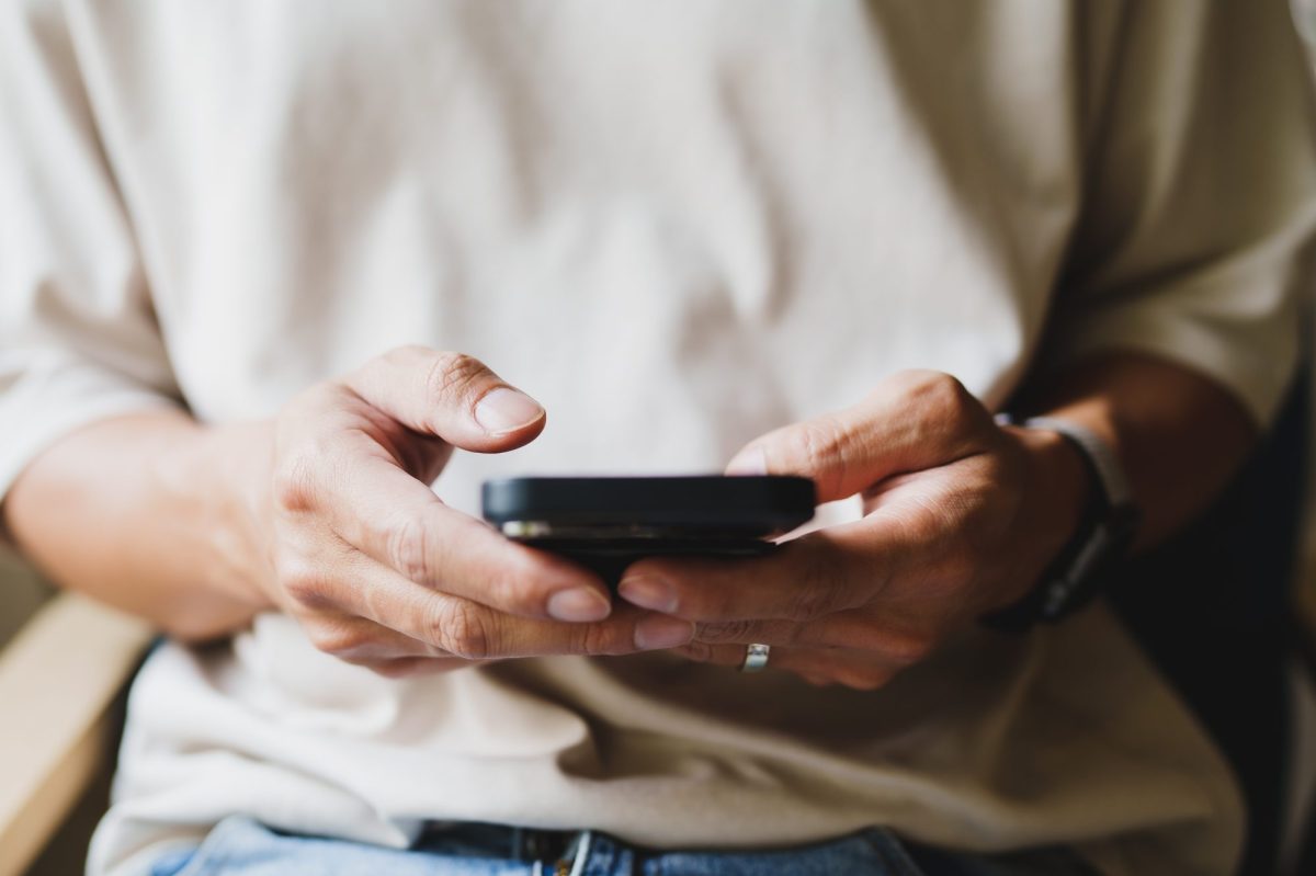 Eine Person tippt mit beiden Händen am Smartphone.