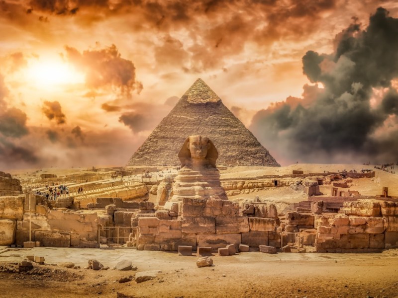 Die Sphinx vor einer Pyramide und mit Staubwolken im Hintergrund