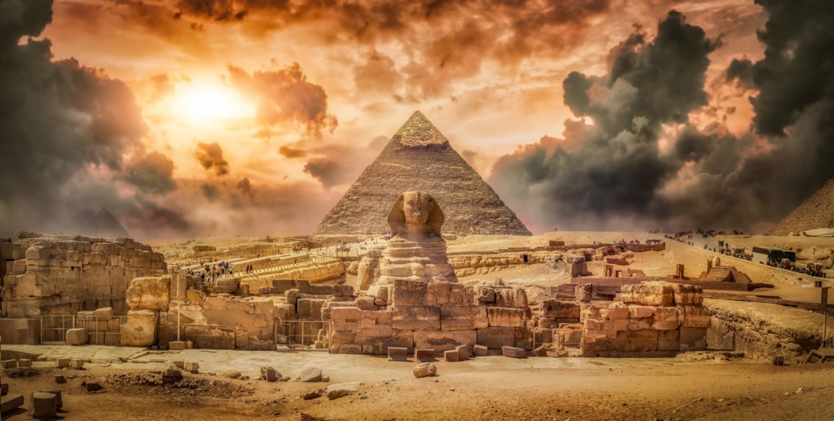 Die Sphinx vor einer Pyramide und mit Staubwolken im Hintergrund
