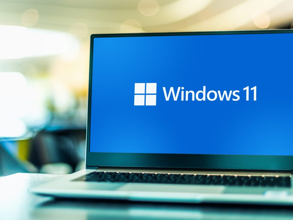 Das Windows 11 Logo auf dem Bildschirm eines Laptops im Büro stehend.