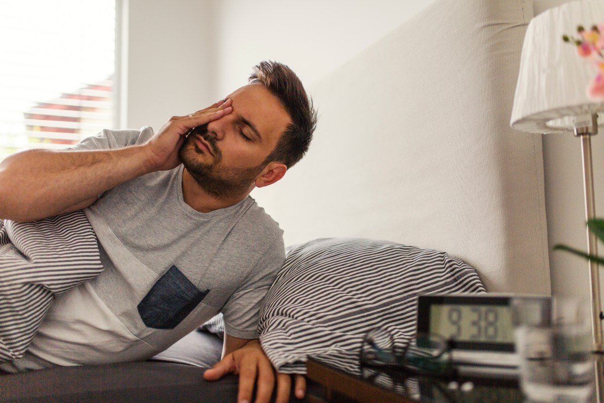 Mann liegt verschlafen im Bett