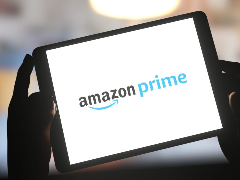 Hände halten ein Tablet, das das Logo von Amazon Prime anzeigt.