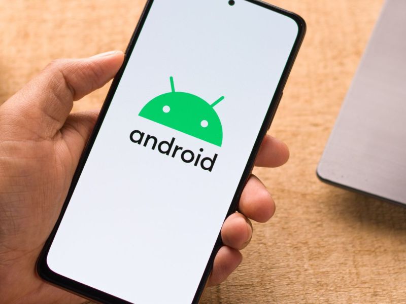 Person hält Smartphone mit Android-Logo in der Hand.