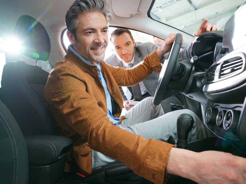 Mann sitzt im Auto und schaut sich etwas an