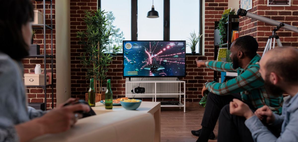 3 Menschen spielen Videospiele auf dem Fernseher.