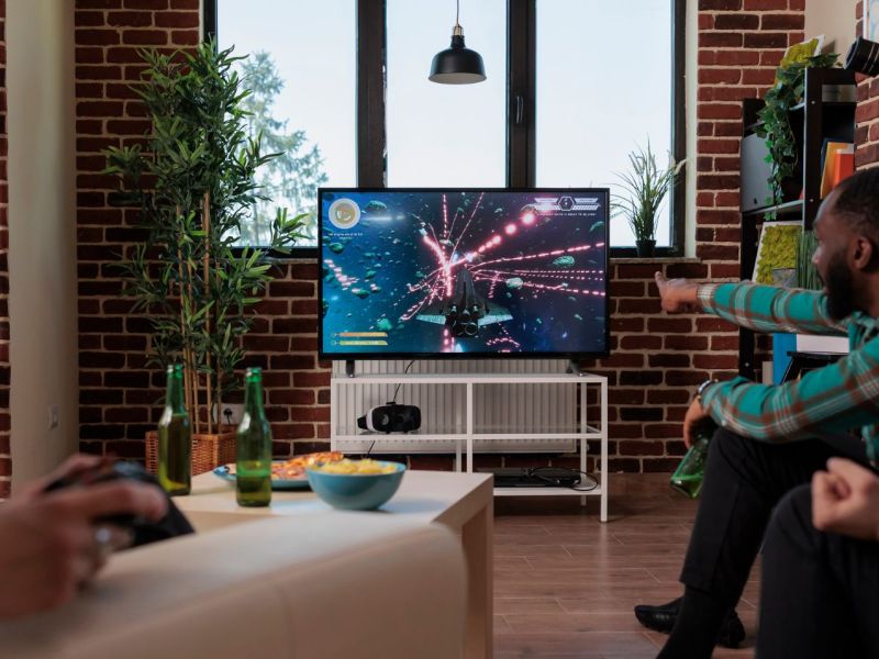 3 Menschen spielen Videospiele auf dem Fernseher.