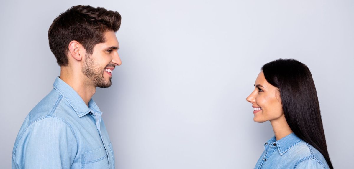 Ein Mann und eine Frau stehen sich gegenüber und schauen sich lächelnd an.