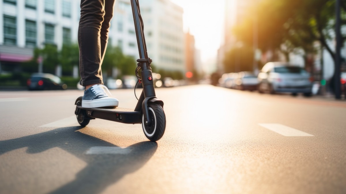 Mann fährt auf E-Scooter über die Straße.