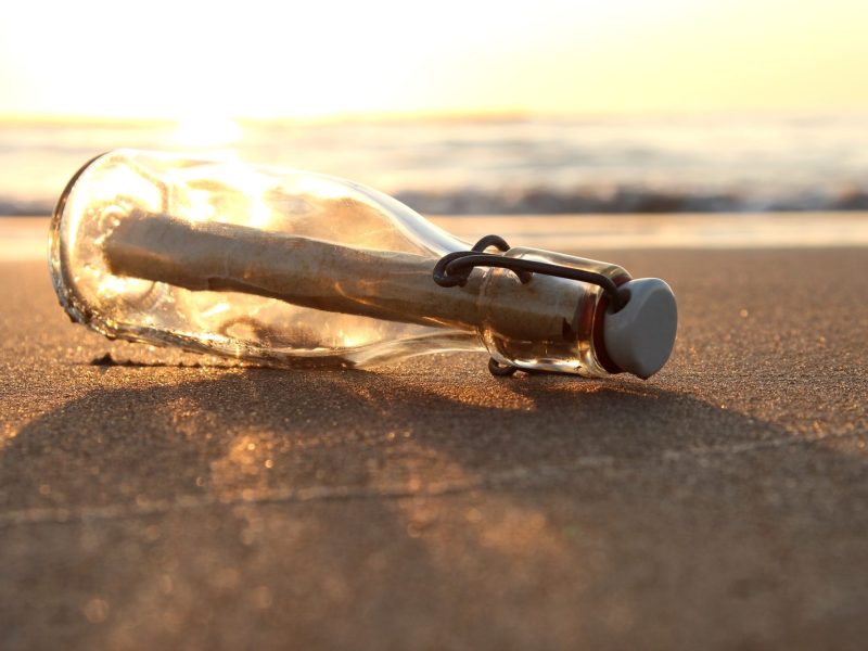 Flaschenpost bei Sonnenuntergang am Strand.