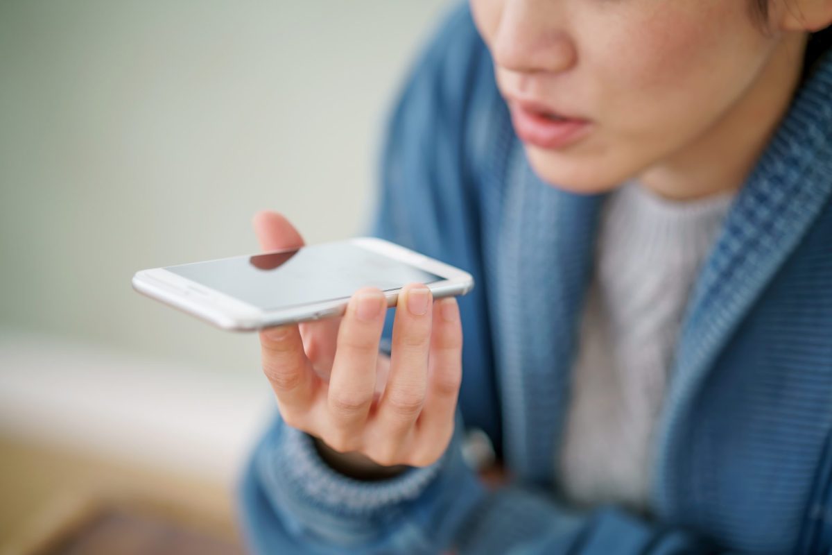 Eine Frau spricht auf ihrem Smartphone mit Siri.