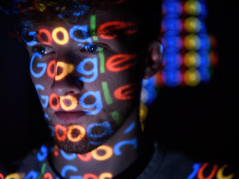 Gesicht eines Mannes, das vom Google-Logo bestrahlt wird