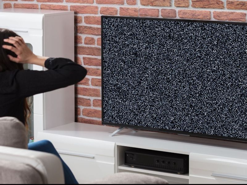Frau schaut auf einen defekten Fernseher