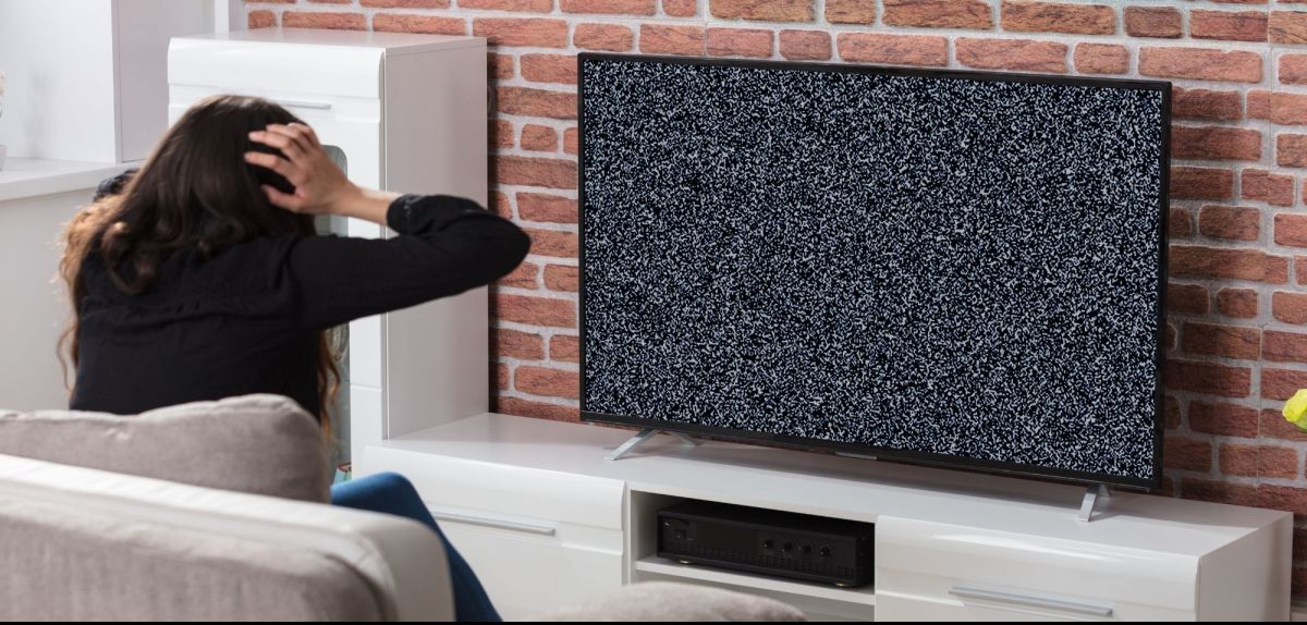Frau schaut auf einen defekten Fernseher
