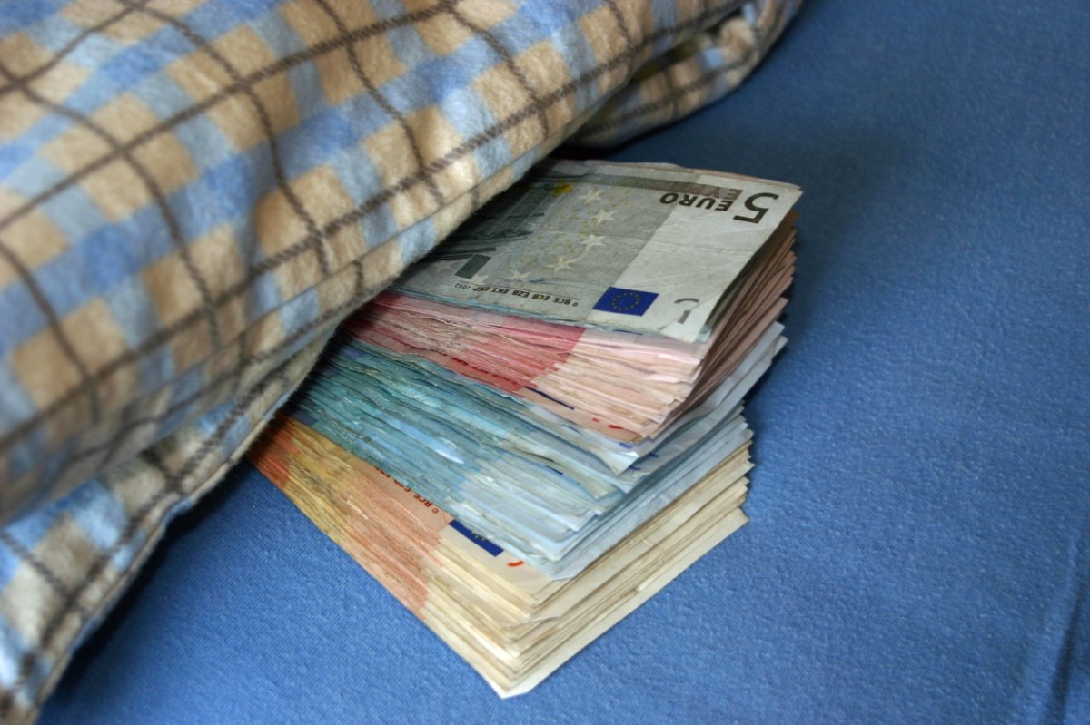 Geldscheine schauen unter einer Bettdecke hervor